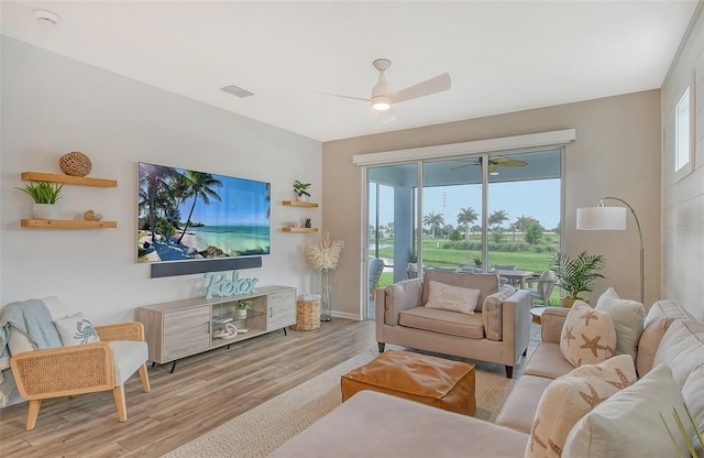 living room with light hardwood / wood-style flooring, ceiling fan, and plenty of natural light