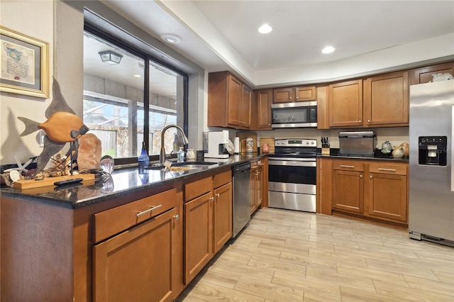 kitchen featuring stainless steel appliances, dark stone counters, and sink