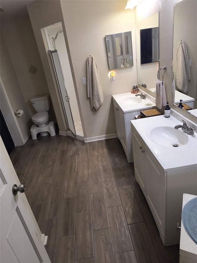 bathroom with hardwood / wood-style floors, vanity, toilet, and walk in shower