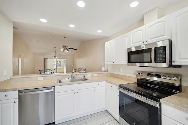 kitchen with kitchen peninsula, stainless steel appliances, vaulted ceiling, and sink