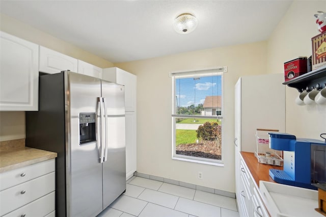 kitchen featuring white cabinets, light tile patterned flooring, butcher block counters, and stainless steel refrigerator with ice dispenser