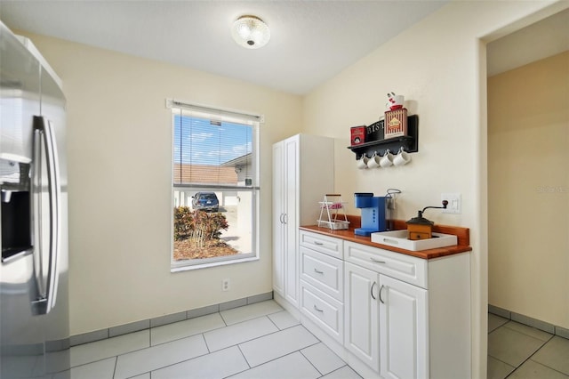 kitchen with white cabinets, stainless steel fridge, and light tile patterned floors