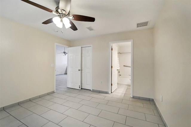 unfurnished bedroom featuring ceiling fan, a closet, light tile patterned floors, and ensuite bathroom