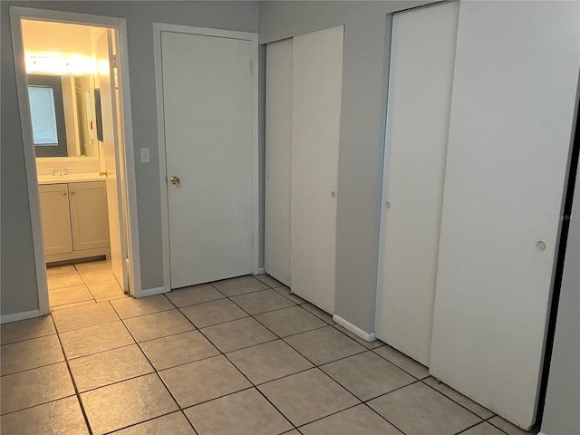 unfurnished bedroom featuring light tile patterned floors, connected bathroom, and multiple closets