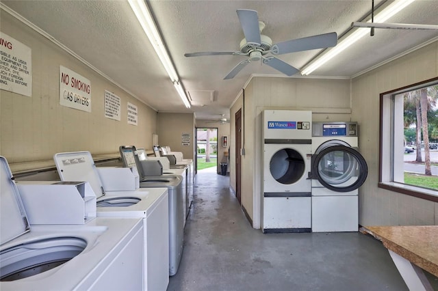 washroom with a textured ceiling, ceiling fan, wooden walls, and washing machine and clothes dryer