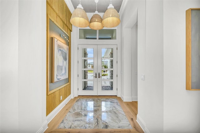 doorway to outside with french doors, ornamental molding, and wooden walls