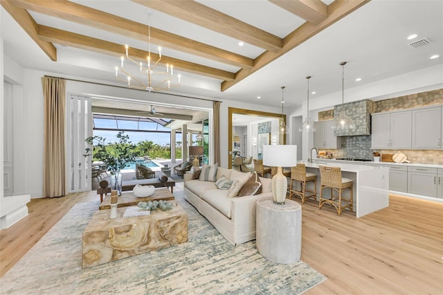 living room with a chandelier, beamed ceiling, and light wood-type flooring