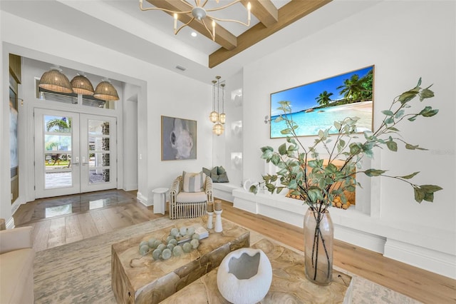 living room featuring a chandelier, wood-type flooring, beam ceiling, and french doors