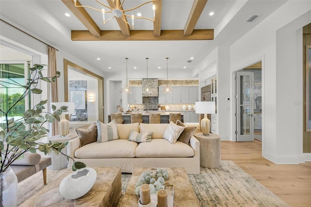 living room featuring light wood-type flooring, beamed ceiling, and a notable chandelier