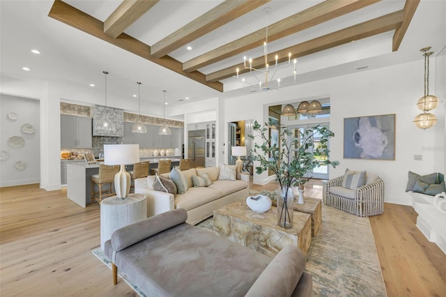 living room with beamed ceiling, light hardwood / wood-style flooring, and an inviting chandelier