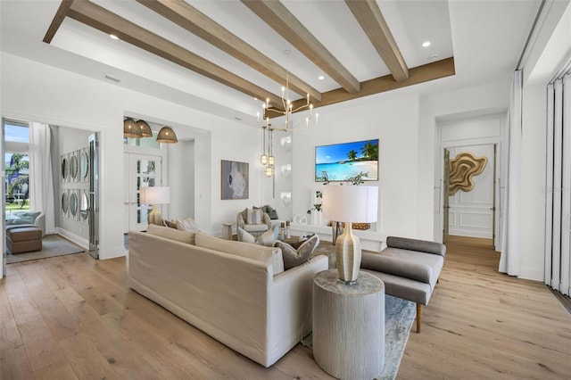 living room with beam ceiling, light hardwood / wood-style floors, and an inviting chandelier