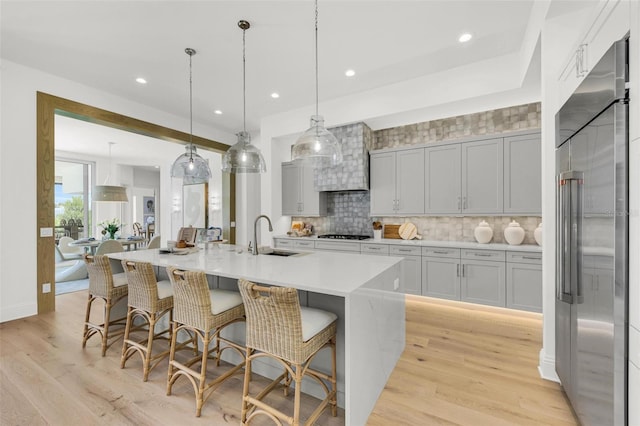 kitchen featuring a spacious island, stainless steel appliances, sink, hanging light fixtures, and a kitchen breakfast bar