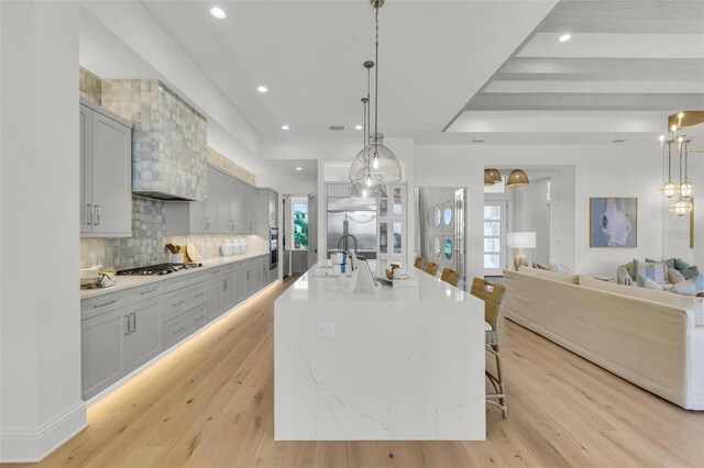 kitchen featuring decorative light fixtures, appliances with stainless steel finishes, a large island, and a breakfast bar area