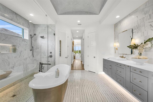 bathroom featuring a wealth of natural light, vanity, tile walls, and plus walk in shower