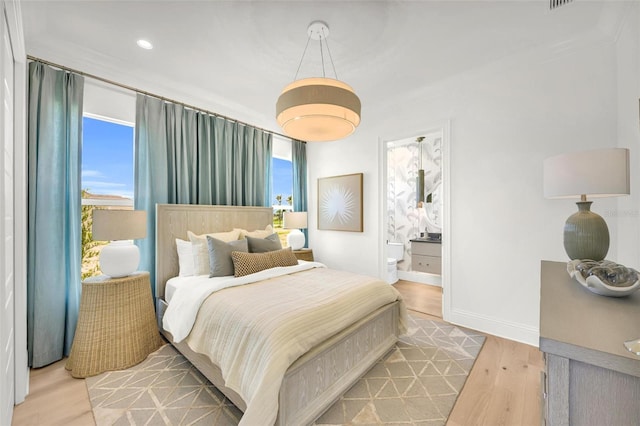 bedroom with light wood-type flooring and ensuite bath