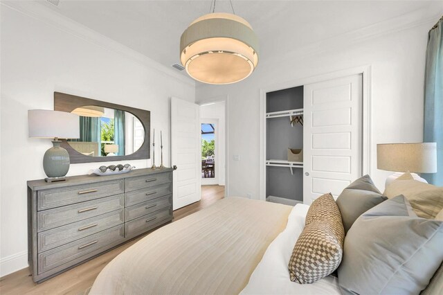 bedroom featuring crown molding, light wood-type flooring, and a closet