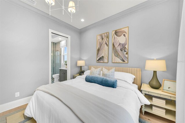 bedroom featuring wood-type flooring, a chandelier, ornamental molding, and ensuite bath