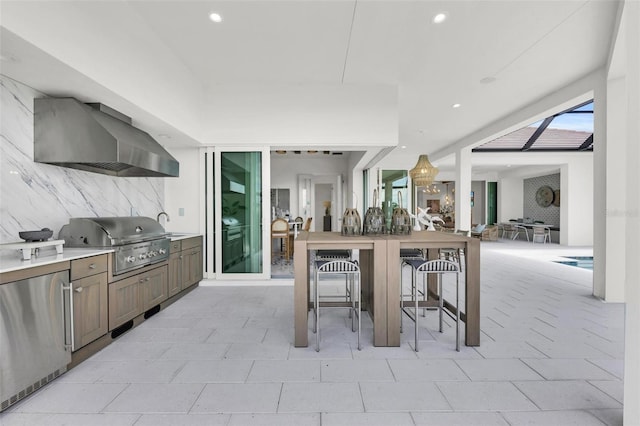 kitchen featuring decorative backsplash, wall chimney range hood, and stainless steel fridge