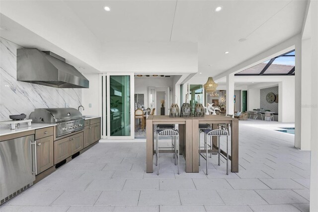 kitchen featuring decorative backsplash, wall chimney range hood, and stainless steel fridge