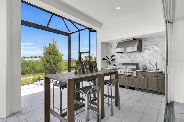 kitchen with sink, wall chimney range hood, and tasteful backsplash