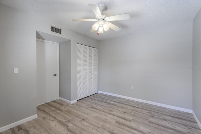 unfurnished bedroom featuring ceiling fan, light wood-type flooring, a closet, and a textured ceiling