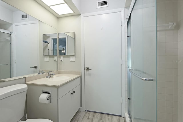 bathroom featuring hardwood / wood-style flooring, vanity, toilet, and walk in shower