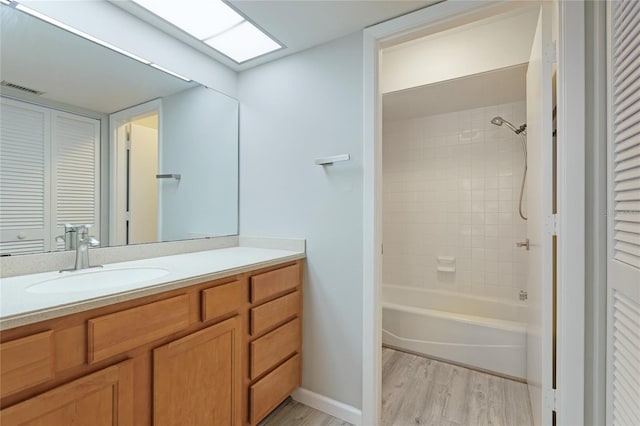 bathroom with tiled shower / bath combo, vanity, a skylight, and hardwood / wood-style floors