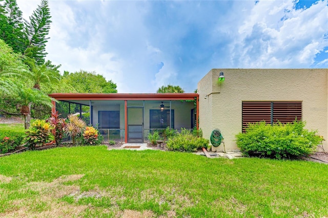 back of property with ceiling fan, a yard, and a sunroom