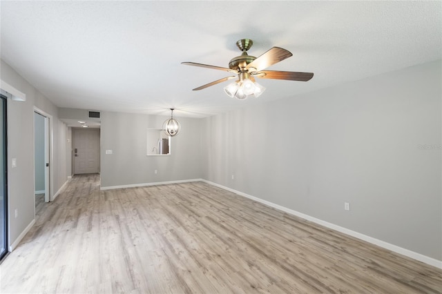 unfurnished room with ceiling fan with notable chandelier, a textured ceiling, and light wood-type flooring