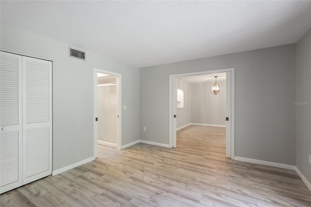 spare room featuring a textured ceiling and light wood-type flooring