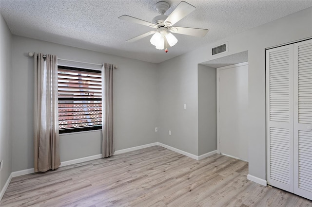 unfurnished bedroom with light wood-type flooring, a textured ceiling, ceiling fan, and a closet