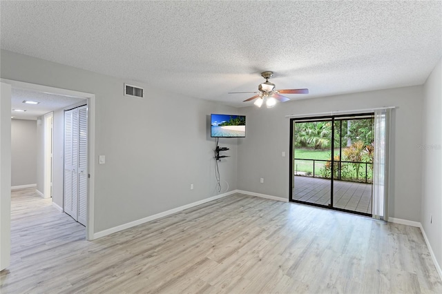 spare room featuring ceiling fan, light hardwood / wood-style flooring, and a textured ceiling