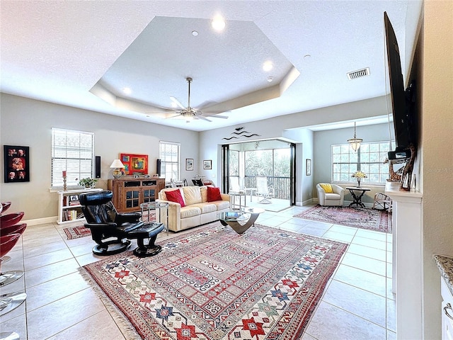 living room featuring visible vents, a raised ceiling, a textured ceiling, and light tile patterned flooring