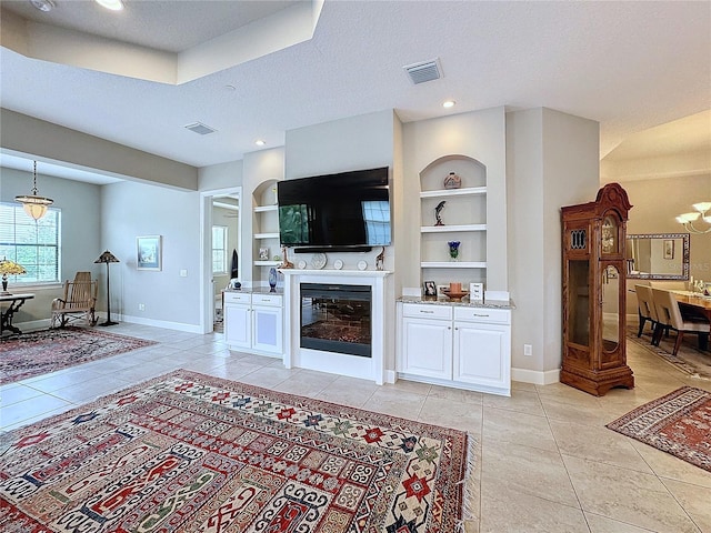 living room with visible vents, built in features, baseboards, and light tile patterned flooring