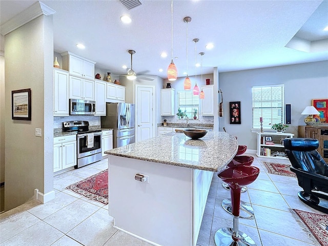 kitchen with light tile patterned floors, a kitchen island, stainless steel appliances, and decorative backsplash