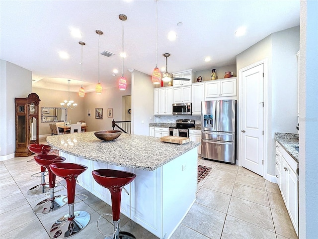 kitchen featuring pendant lighting, a large island, stainless steel appliances, visible vents, and a kitchen breakfast bar