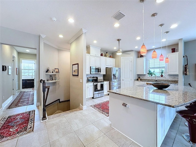 kitchen with white cabinets, a healthy amount of sunlight, a kitchen island, and stainless steel appliances