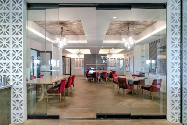 dining area featuring brick ceiling, a tray ceiling, and a notable chandelier