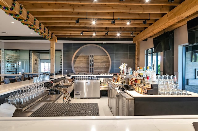 interior space with beamed ceiling, a dry bar, and track lighting