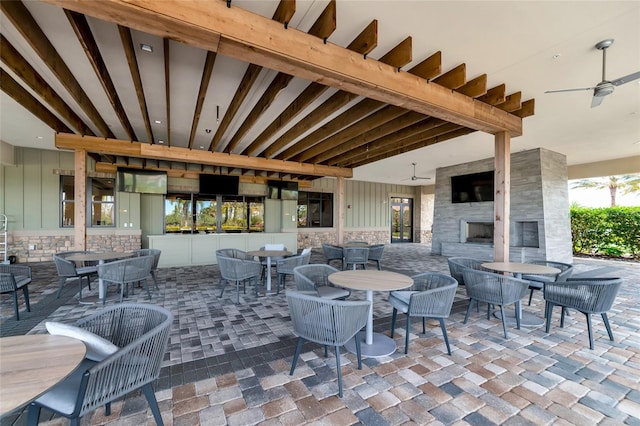 view of patio / terrace featuring a large fireplace, outdoor dining area, and a ceiling fan