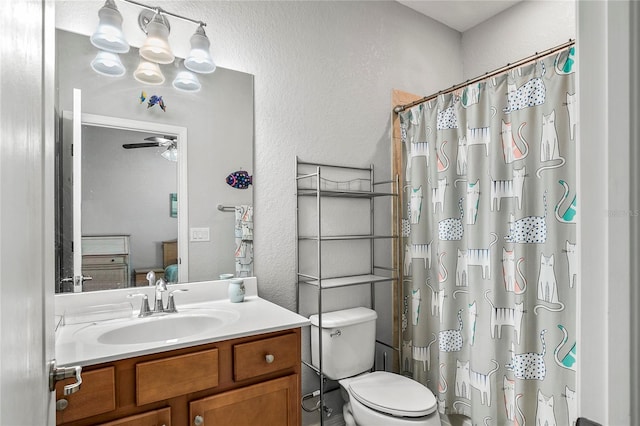 bathroom with a shower with curtain, ceiling fan, vanity, and toilet