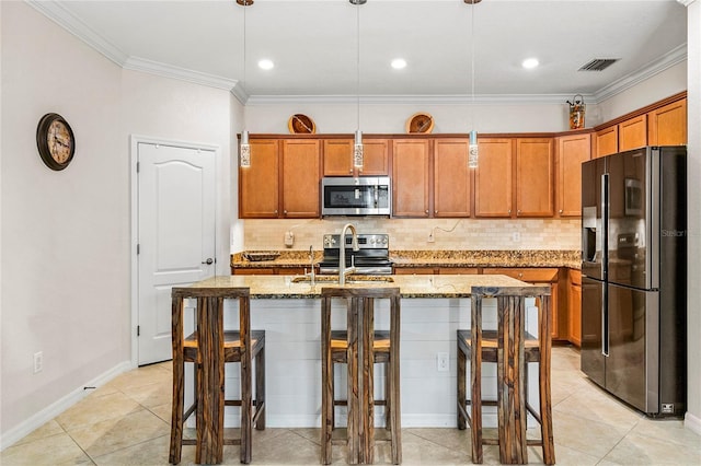 kitchen featuring pendant lighting, stainless steel appliances, light stone counters, and a center island with sink