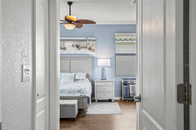 bedroom featuring hardwood / wood-style floors, ceiling fan, and crown molding