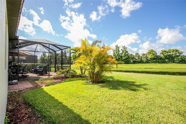 view of yard featuring glass enclosure, a patio area, and a water view