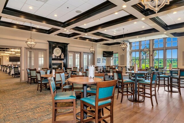 dining room with a high ceiling, a large fireplace, french doors, and beam ceiling