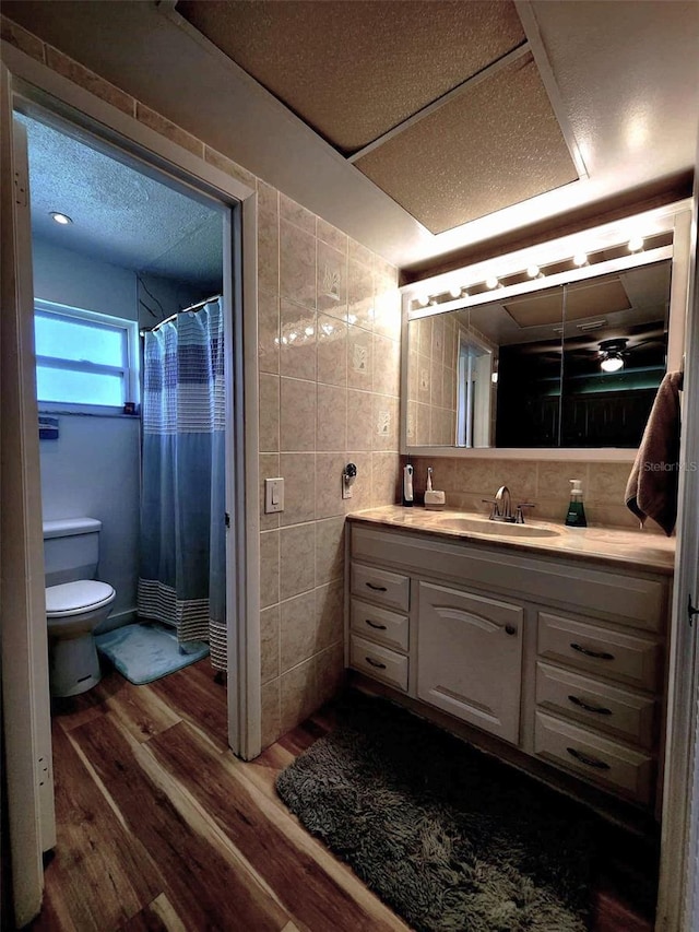 bathroom featuring hardwood / wood-style floors, vanity, a shower with curtain, tile walls, and toilet