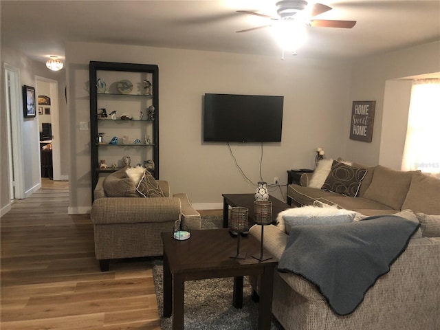 living area featuring wood finished floors, a ceiling fan, and baseboards