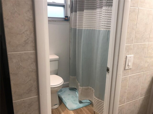 bathroom with toilet, a shower with curtain, and hardwood / wood-style flooring