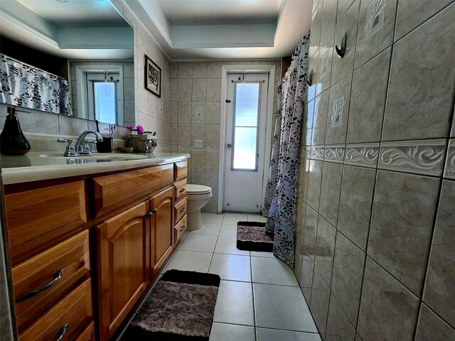 bathroom with tile walls, toilet, vanity, and tile patterned flooring