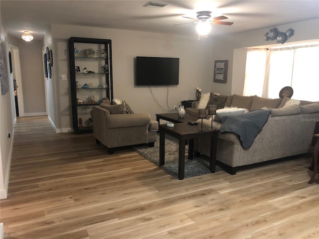 living room featuring light wood-style floors, visible vents, and a ceiling fan